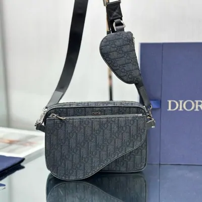 A grey monogram belt bag with its shoulder strap, standing beside its box
