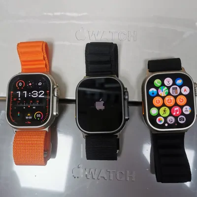 Three smartwatches side by side with orange, black and grey straps